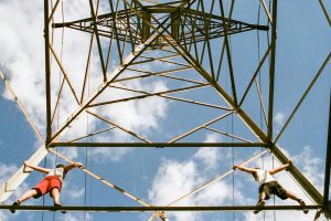 Power line tower with two men climbing it