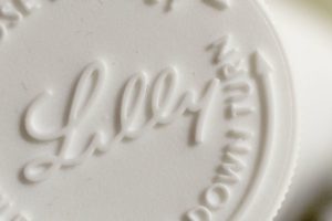 AN EXTREME CLOSE UP OF A CHALKY, WHITE PILL STAMPED WITH THE NAME LILLY