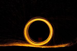 Burning steel wool being swirled in a circle at night to form a zero with slow exposure